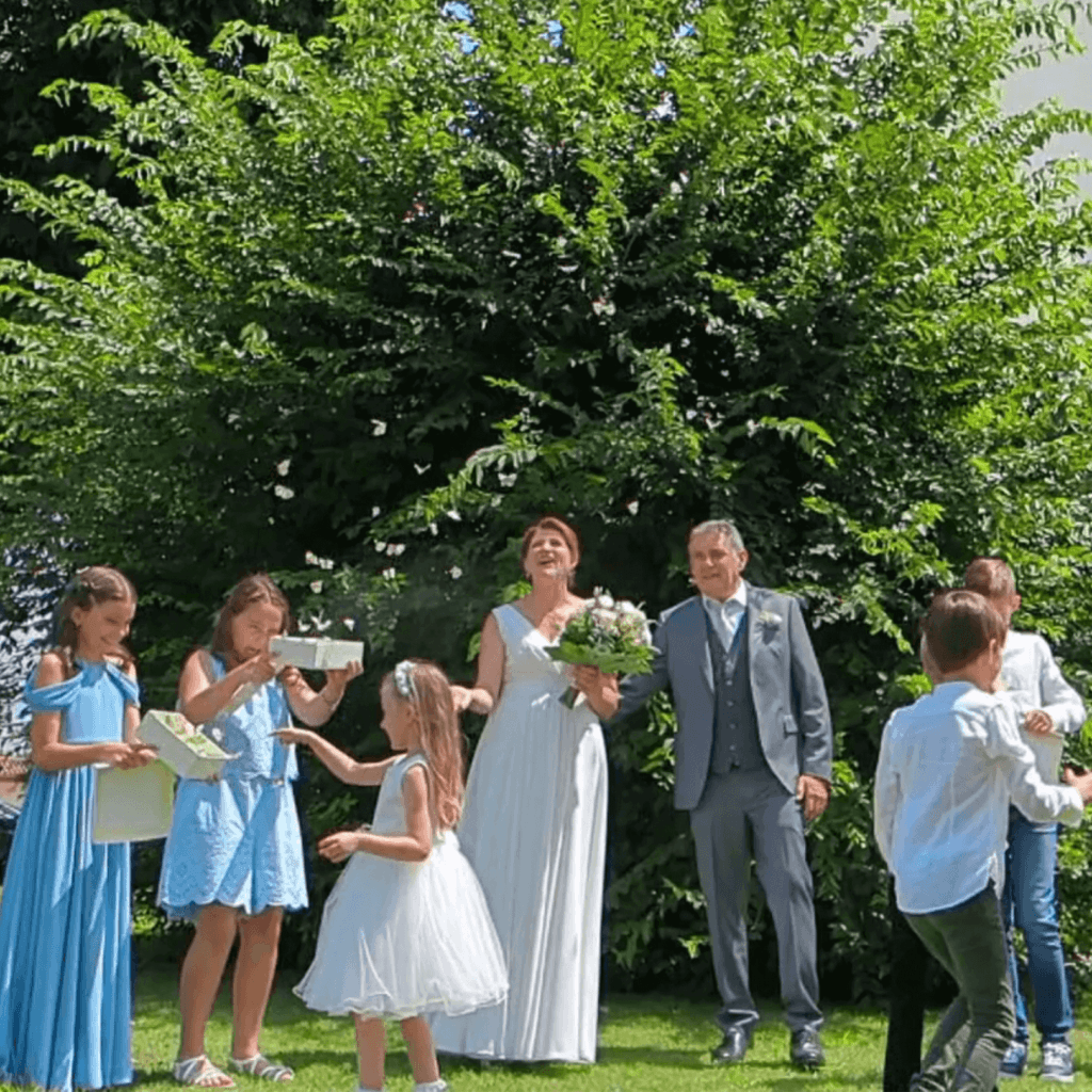 Sposi e giovani invitati liberano farfalle bianche durante il matrimonio